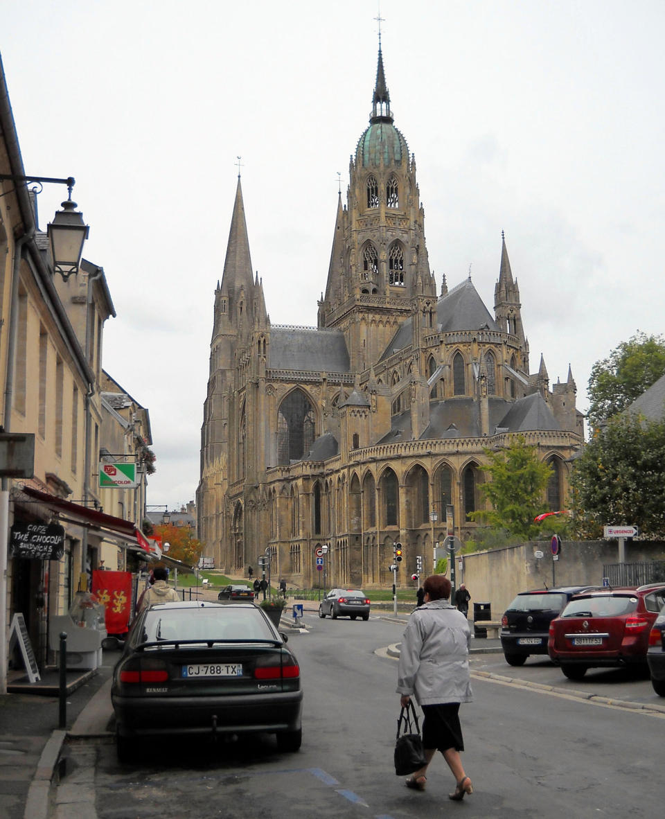 This Oct. 11, 2013 photo shows a pedestrian walking near the cathedral in Bayeux, France. The cathedral was consecrated in 1077 in the presence of William the Conqueror, duke of Normandy and king of England. (AP Photo/Kathy Matheson)