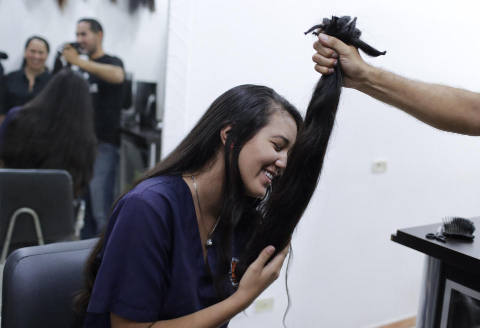 Valery Díaz holds the hair she had cut off to earn $100 in Caracas, Venezuela, Friday, April 5, 2019. After a drastic cut of 60 centimeters that was reduced to less than two, Díaz looked silently into the mirror at what hair remained, as her mother encouraged her that the cut was hardly noticeable. (AP Photo/Natacha Pisarenko)