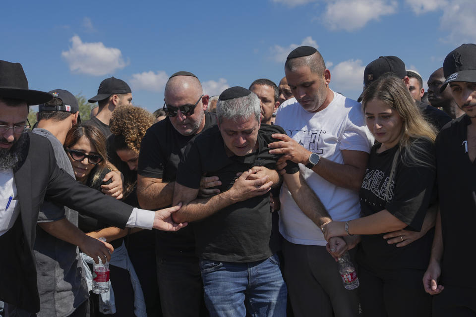 Relatives of Naor Hassidim mourn around his grave during his funeral in Ashdod, Israel, Monday, Oct. 16, 2023. Hassidim and his partner were killed by Hamas militants on Oct. 7 in Kibbutz Kfar Azza, close to the Gaza Strip's separation fence with Israel, as the militant Hamas rulers of the territory carried out an unprecedented, multi-front attack that killed over 1,300 and captured many Israelis. (AP Photo/Tsafrir Abayov)