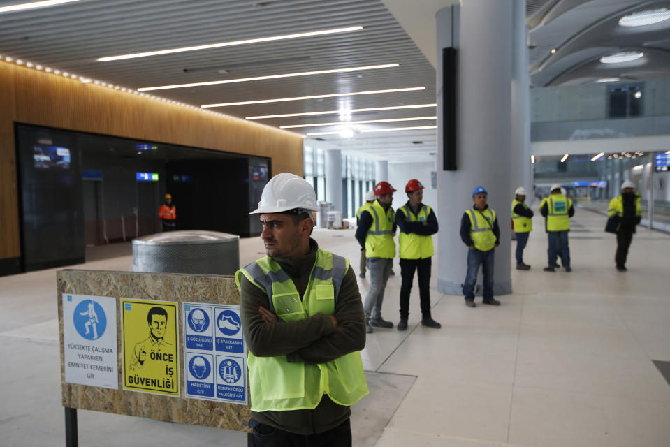 FILE - In this April 13, 2018, file photo, construction workers stand in one of the terminals of Istanbul's third international airport. The first phase of the airport, one of Turkey's President Recep Tayyip Erdogan's major construction projects, is scheduled to be inaugurated on Oct. 29 when Turkey celebrates Republic Day. The massive project, has been mired in controversy over worker's rights and environmental concerns amid a weakening economy. (AP Photo/Lefteris Pitarakis, File)