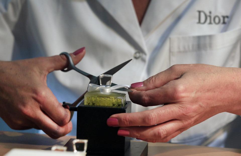 A Dior perfume worker seals a flacon of scent at the Dior fashion house in Paris, in this photo dated Friday June 14, 2013, as part of the Les Journees Particulieres, event organised for two days by LVMH group. More than forty LVMH group locations throughout Europe are opening their doors and inviting the public to discover the savoir-faire of the luxury fashion industry group, for a two day open-door event. (AP Photo/Remy de la Mauviniere)