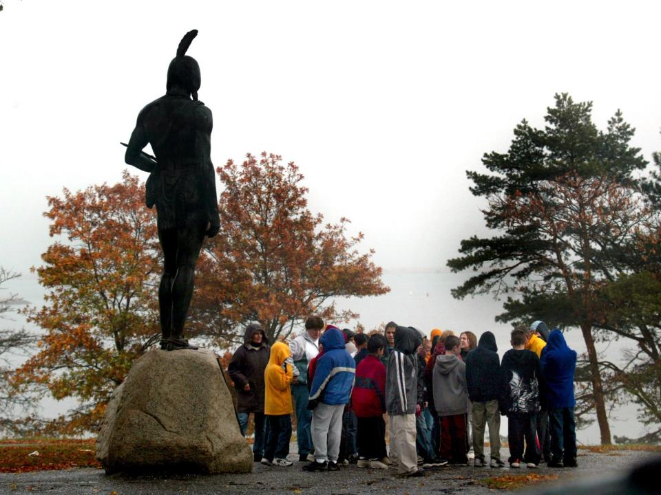 A group of school kids gather at the statue of Massasoit, "Great Sachem of the Wampanoag's," on the hill overlooking Plymouth Rock and the harbor.