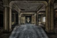 <p>Tall pillars cast ominous shadows in this former reception space.</p>