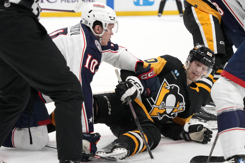 Pittsburgh Penguins' Lars Eller (20) and Columbus Blue Jackets' Dmitri Voronkov (10) work from the ice after a faceoff during the second period of an NHL hockey game in Pittsburgh, Tuesday, March 5, 2024. (AP Photo/Gene J. Puskar)