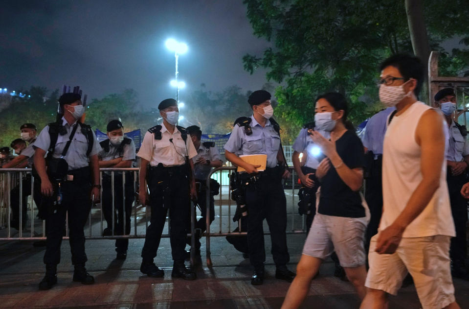 People hold candles and walk past police officers near Victoria Park, a place in the past years for people to gather during a candlelight vigil to mark the anniversary of the military crackdown on a pro-democracy student movement in Beijing, in Hong Kong, Friday, June 4, 2021. A member of the committee that organizes Hong Kong's annual candlelight vigil for the victims of the Tiananmen Square crackdown was arrested early Friday on the 32nd anniversary. (AP Photo/Vincent Yu)