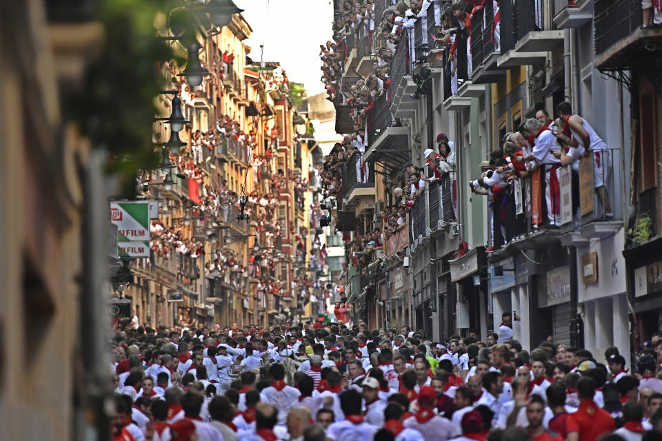 Gente corriendo por la calle por delante de los toros bravos en el primer día de encierros en las fiestas de San Fermín, Pamplona, en el norte de España, el jueves 7 de julio de 2022. (AP Foto/Álvaro Barrientos)