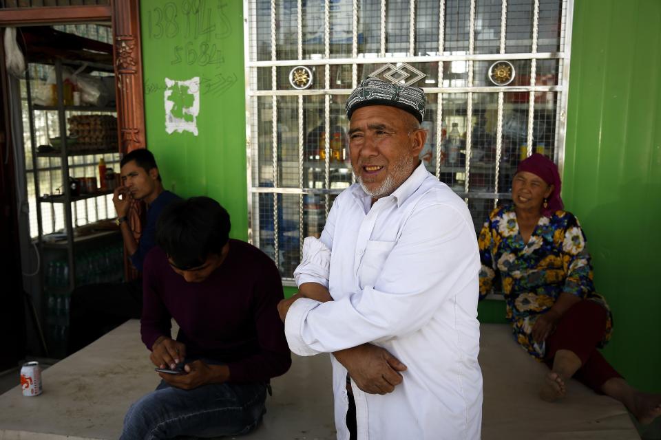 FILE - Muzitohtahon, center, an Uyghur farmer in his early seventies who moved to the village three years ago, said he is no longer a Muslim, stands outside a convenience store at the Unity New Village in Hotan, in western China's Xinjiang region on Sept. 21, 2018. Authorities in China's western Xinjiang region have been systematically replacing the names of villages inhabited by Uyghurs and other ethnic minorities to reflect the ruling Communist Party's ideology, as part of an attack on their cultural identity, according to a report released Wednesday, June 19, 2024, by Human Rights Watch. (AP Photo/Andy Wong, File)