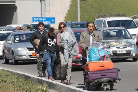 People walk through traffic along a highway as taxi drivers (not pictured) block the way to Santiago's international airport during a protest against Uber and Cabify technologies in Santiago, Chile September 4, 2017. REUTERS/Stringer