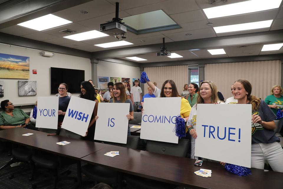 Participants hold up signs announcing that Mark "Swaggy" Lane's wish was being granted by Make a Wish Georgia on Wednesday at the Savannah Area Chamber of Commerce on Bay Street in Savannah, Georgia.
