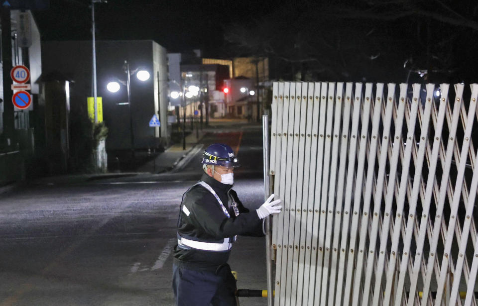 A guard opens the gate to the town in Futaba, Fukushima prefecture, northern Japan at midnight Wednesday, March 4, 2020. Japan’s government partially lifted an entry ban for Futaba, the last town that remained off-limits since it was entirely forced to evacuate following the Fukushima nuclear disaster nine years ago. (Kyodo News via AP)
