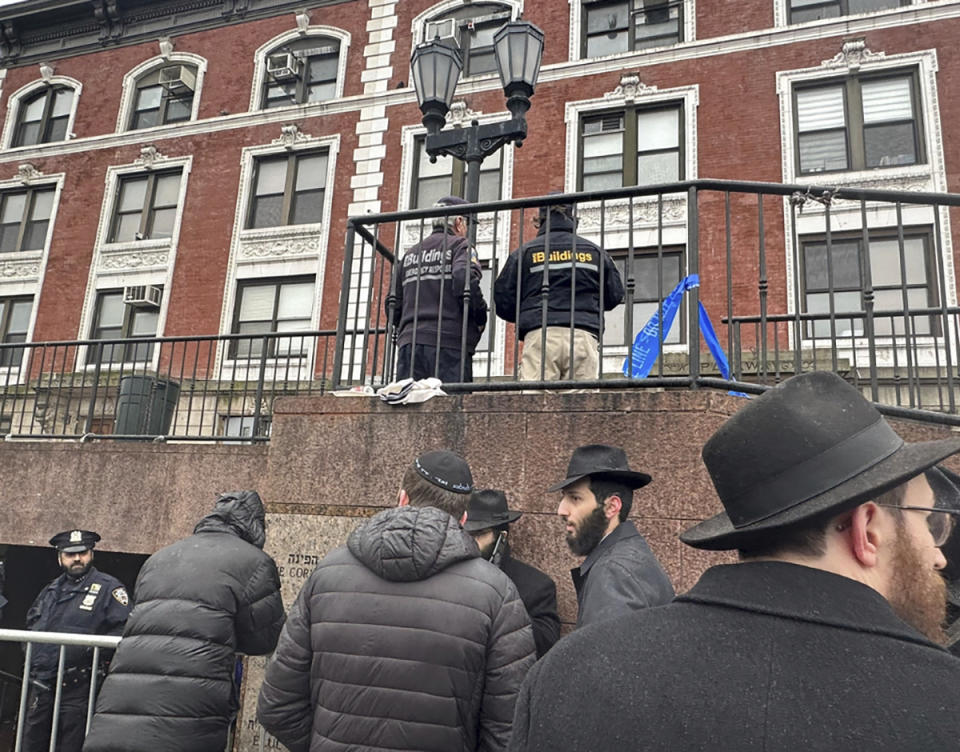 FILE - City inspectors and police officers outside the Brooklyn borough, N.Y., headquarters of the Chabad movement, Tuesday, Jan. 9, 2024. On Friday, Jan. 12, The Associated Press reported on stories circulating online incorrectly claiming a secret underground tunnel found connected to the Chabad Lubavitch World Headquarters was used for child sex trafficking or other illicit activities.(AP Photo/Jake Offenhartz)