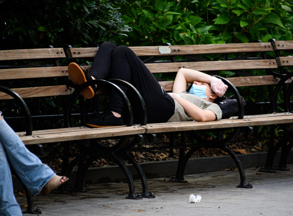 NEW YORK, NEW YORK - AUGUST 08: A person wearing a protective face mask and gloves sleeps in Madison Square Park as the city continues Phase 4 of re-opening following restrictions imposed to slow the spread of coronavirus on August 8, 2020 in New York City. The fourth phase allows outdoor arts and entertainment, sporting events without fans and media production. (Photo by Noam Galai/Getty Images)