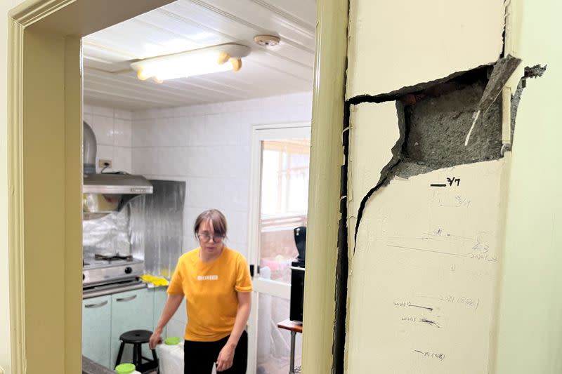 Linda Chen, 48, walks near the damaged walls with marks tracking her son's height over time, while collecting valuables from her apartment following the earthquake, in Hualien