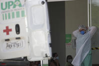 A health worker prepares to receive a COVID-19 patient at the Luziania field hospital, a suburb of Brasilia, Brazil, Thursday, Feb. 25, 2021. With the cities on the borders of Brasilia in a state of calamity due to the pandemic and with high occupancy at ICU units, mayors want to implement more rigid restrictions and limit access to the capital where many of their residents work. (AP Photo/Eraldo Peres)