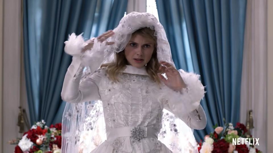 A woman lifts the veil of her wedding dress.