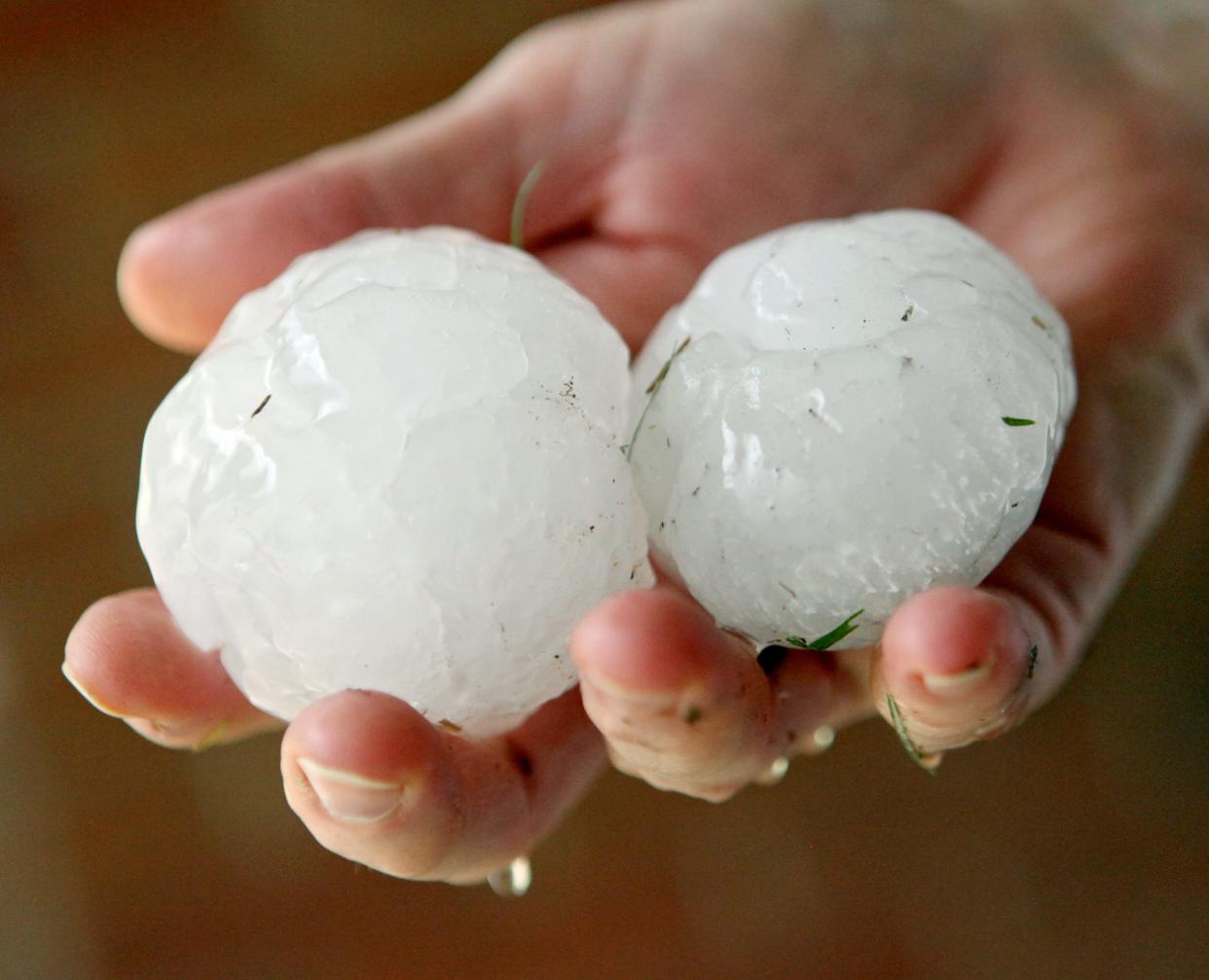 A resident of The Village holds large hail stones outside her home during a spring storm.