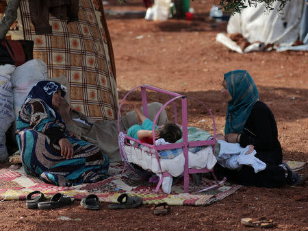Two displaced Syrian women from the al-Ahmed family sit together in an olive grove in the town of Atmeh, Idlib province, Syria, May 16, 2019. REUTERS/Khalil Ashawi
