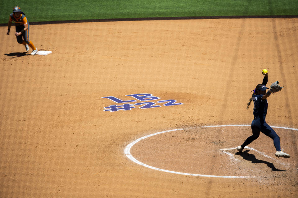 FILE - "LB #22," in honor of James Madison softball catcher Lauren Bernett, is written on the infield behind Liberty pitcher Emily Kirby, right, during an NCAA college softball game against Tennessee at Liberty Softball Stadium in Lynchburg, Va., April 27, 2022. There has been a lot of talk about the mental health struggles that many young athletes face, the pressures and vulnerabilities that can seem overwhelming — especially to those who feel compelled to shield their pain from the outside world. (Kendall Warner/The News & Advance via AP, File)