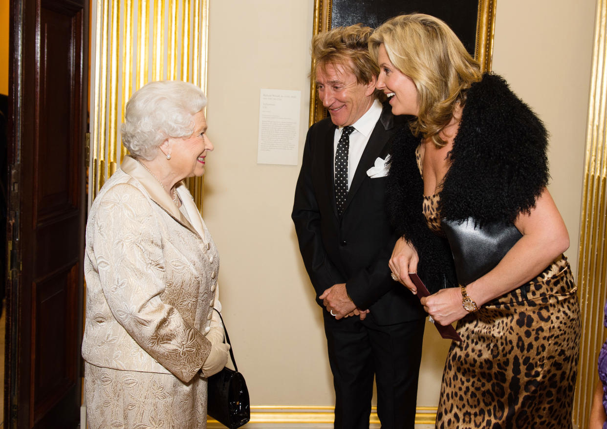 Queen Elizabeth II greets Sir Rod Stewart and wife Penny Lancaster at an awards ceremony in 2016. (Getty Images)