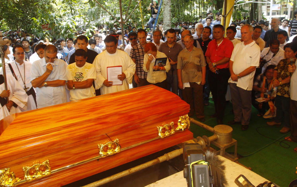 FILE - In this Oct. 25, 2011 file photo, a crowd gather in Kidapawan township as slain Italian priest Rev. Fausto Tentorio is laid in a coffin to rest in North Cotabato province in southern Philippines. The dead last year included Tentorio, an Italian Catholic priest who fought against mining companies to protect the ancestral lands of the Manobo tribe in the southern Philippines. Affectionately known as "Father Pops," he was buried in the coffin made from a favorite mahogany tree he had planted. (AP Photo/File)