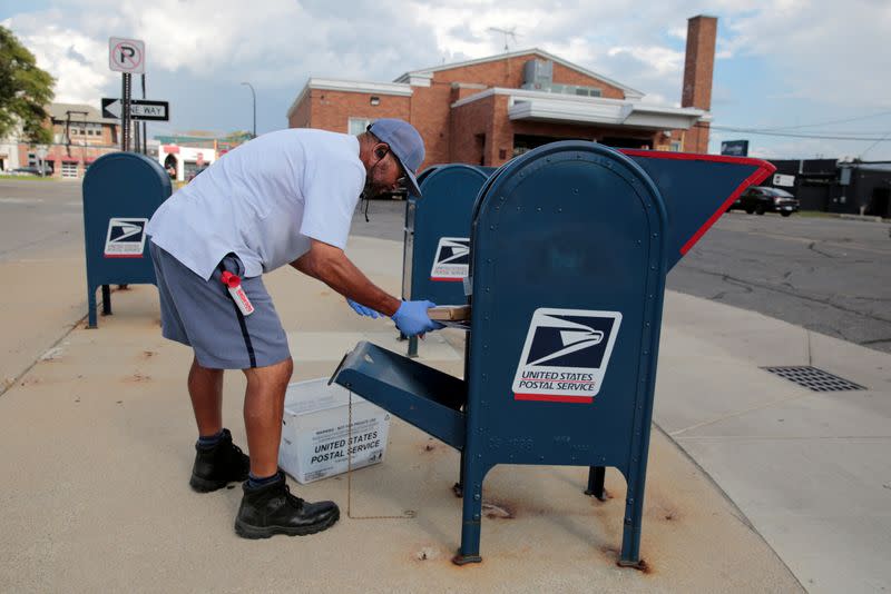 FILE PHOTO: A United States Postal Service (USPS) worker handles the mail in a drop-off box