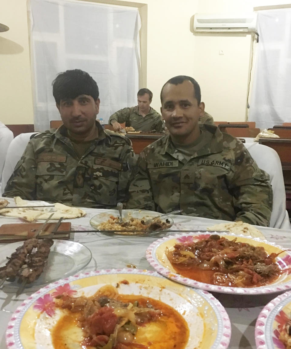 In this undated photo provided by Ryan Brummond, Mohammad Khalid Wardak, left, poses with a U.S. solider in Afghanistan. Khalid, as he's called by his friends, had no intention of leaving Afghanistan, where he was a high-profile national police officer who'd worked alongside American special forces to defeat the Taliban. Then with stunning speed, his government collapsed. Now he is in hiding with his wife and four children, wounded and hunted by the Taliban, desperately hoping that American officials will repay his loyalty by helping his family escape almost certain death. (Ryan Brummond via AP)