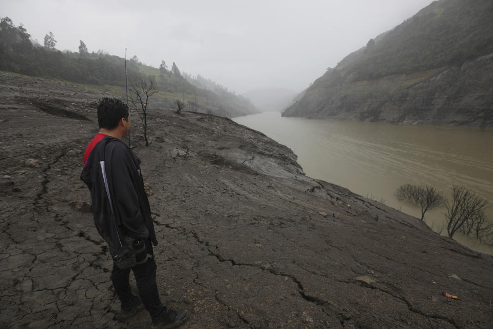 Un hombre se encuentra en las orillas expuestas del embalse de Mazar, en la provincia de Azuay de Ecuador, el miércoles 17 de abril de 2024. Ecuador comenzó el martes a racionar la electricidad en las principales ciudades del país debido a que una sequía limita la producción en las plantas hidroeléctricas. (AP Foto/Xavier Caivinagua)