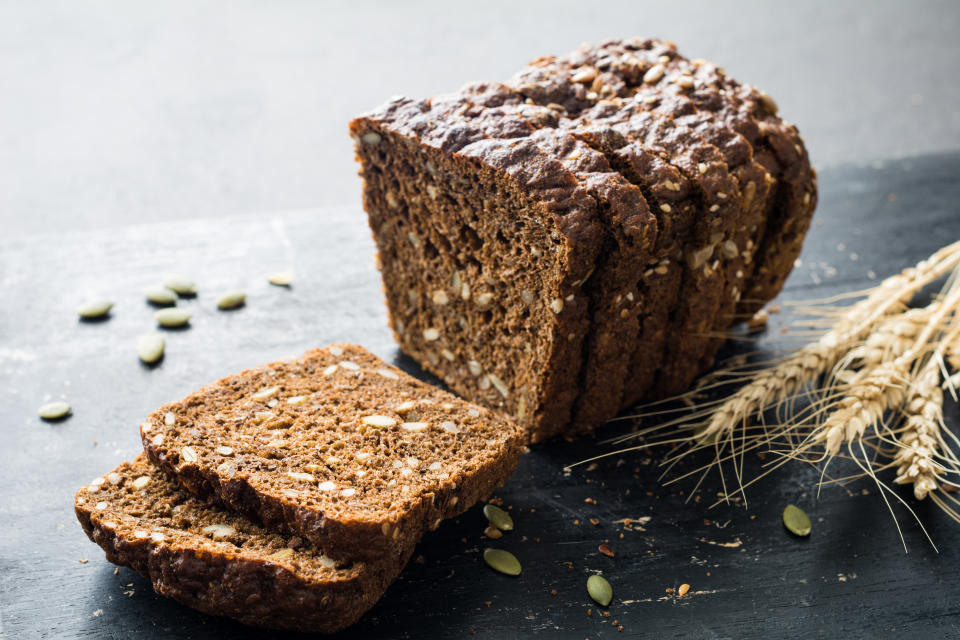 Whole grain rye bread with seeds on blackboard. Closeup view, selective focus