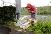 A man prays after placing flowers near the torced Kyoto Animation building to mourn the victims of the arson attack in Kyoto