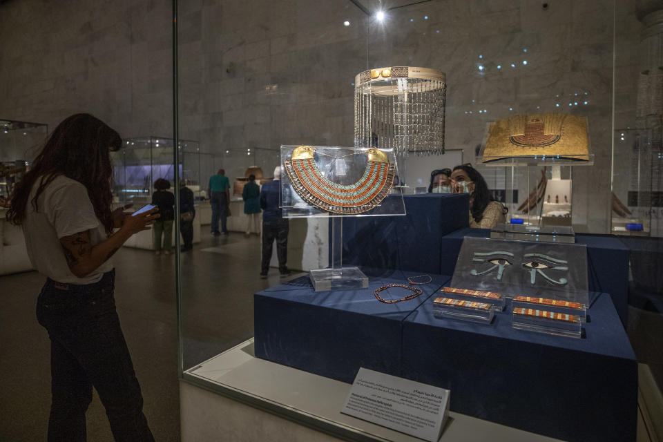 FILE - In this April 24, 2021 file photo, women look at a collection of the jewelry of Princess Neferuptah, the daughter of King Amenemhat III, on display in its glass case at the new National Museum of Egyptian Civilization in Old Cairo. As some European countries re-open to international tourists, Egypt has already been trying for months to attract them to its archaeological sites and museums. Officials are betting that the new ancient discoveries will set it apart on the mid- and post-pandemic tourism market (AP Photo/Nariman El-Mofty, File)