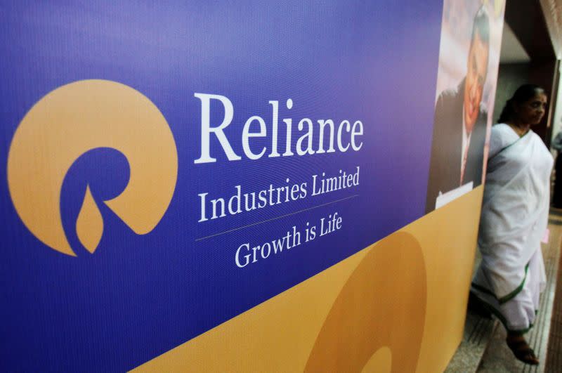 FILE PHOTO: A woman walks past a poster of Reliance Industries installed outside the venue of the company's annual general meeting in Mumbai