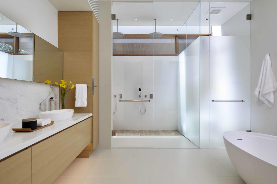 A bathroom in all white, with wooden vanity and a cabinet