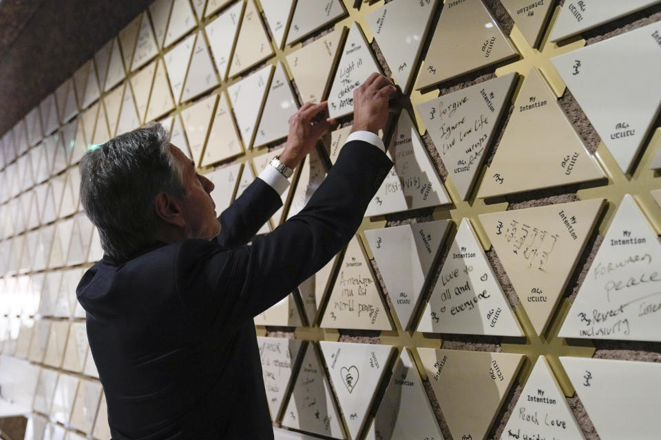 U.S. Secretary of State Antony Blinken puts a tile on the intention wall at the Abrahamic Family House, in Abu Dhabi, United Arab Emirates, Saturday Oct. 14, 2023. Blinken wrote "Light in the darkness" on the tile before placing it on the wall. (AP Photo/Jacquelyn Martin, Pool)