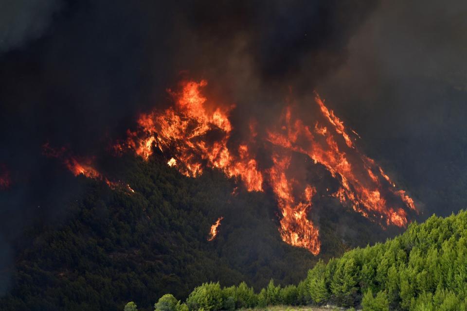 Flames burn a mountain in Platanos village, near ancient Olympia, western Greece, Wednesday, Aug. 4, 2021. The European Union promised assistance Wednesday to Greece and other countries in southeast Europe grappling with huge wildfires after a blaze gutted or damaged more than 100 homes and businesses near Athens. (Giannis Spyrounis/ilialive.gr via AP)