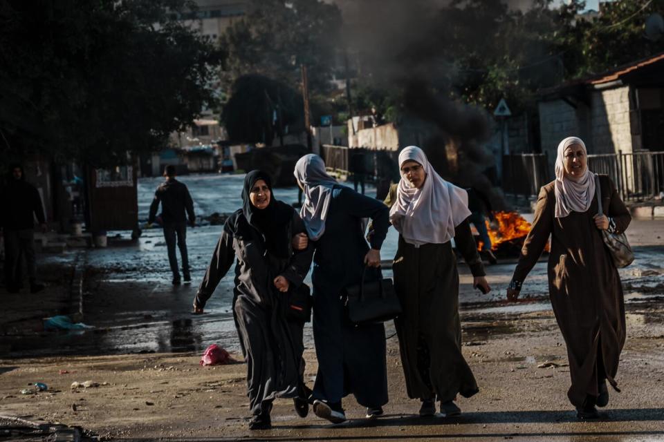 Several women run down a street.