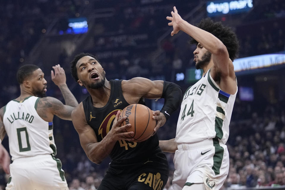 Cleveland Cavaliers guard Donovan Mitchell, center, drives between Milwaukee Bucks guards Damian Lillard (0) and Andre Jackson Jr. (44) during the first half of an NBA basketball game, Wednesday, Jan. 17, 2024, in Cleveland. (AP Photo/Sue Ogrocki)