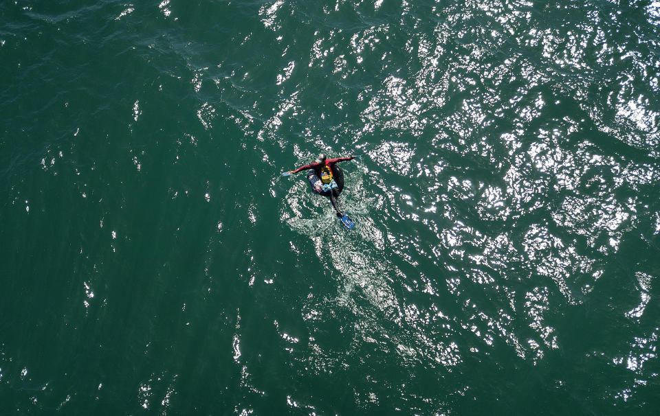 Eric Mendez, a 40-year-old bricklayer, floats on his inner tube while open sea fishing in Playa Escondida in La Guaira, Venezuela, Friday, Aug. 14, 2020, amid the new coronavirus pandemic. Aside from the risks, the fishermen on inner tubes say being at sea for several hours brings a calm. They're far from the struggles of life on land — the growing COVID-19 pandemic, economic crisis, hungry children and no work. (AP Photo/Matias Delacroix)