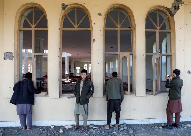 Men watch a damaged mosque at the site of an attack in a U.S. military air base in Bagram