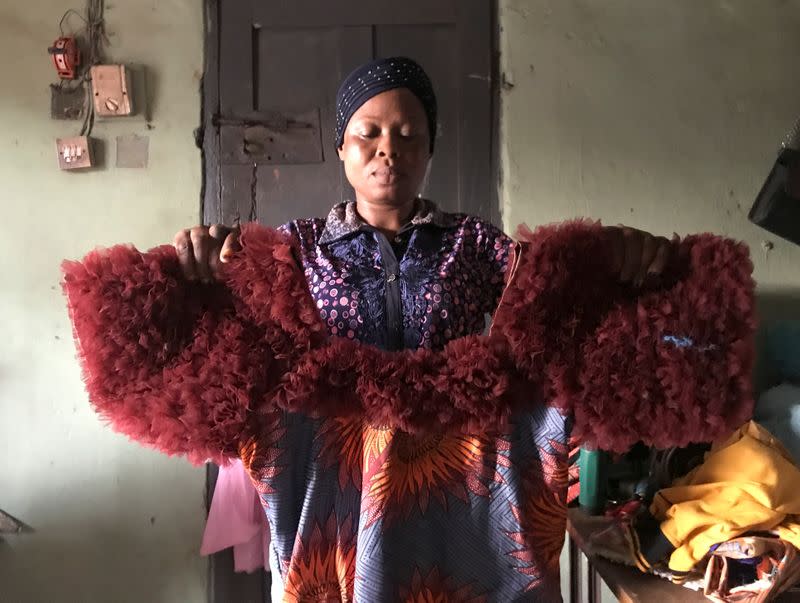 Kemi Adepoju, a dressmaker, poses with a dress in her shop amid the spread of the coronavirus disease (COVID-19) in Lagos