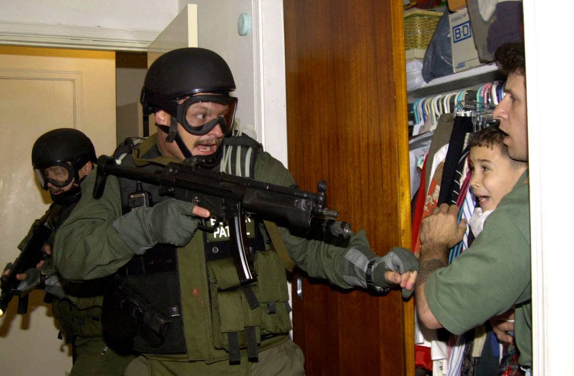 In this file photo taken April 22, 2000, in Miami, Elián González is held in a closet by Donato Dalrymple, one of the two men who rescued the boy from the ocean, right, as government officials search the home of Lazaro González for the young boy. The boy was eventually reunited with his father in Cuba, but the ordeal put a spotlight on bitter relations between the U.S. and Cuba. (AP Photo/Alan Diaz, File)