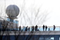 Passengers stand on the deck of the quarantined Diamond Princess cruise ship anchored at a port in Yokohama, near Tokyo, Thursday, Feb. 20, 2020. Passengers tested negative for COVID-19 started disembarking since Wednesday. (AP Photo/Eugene Hoshiko)