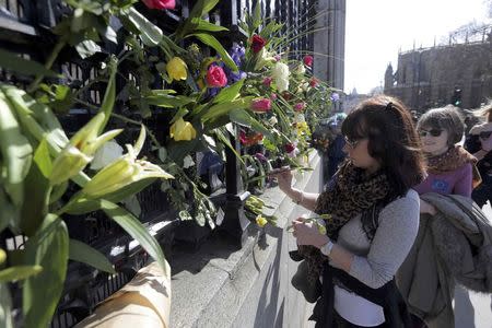 A woman adds a flower to the tributes at the fence surrounding the House of Parliament, following the attack in Westminster earlier in the week, in London, Britain March 25, 2017. REUTERS/Paul Hackett