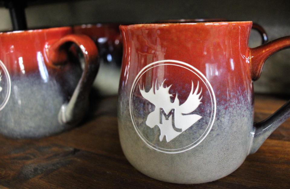 Ceramic coffee cups with Moose Mountain branding.