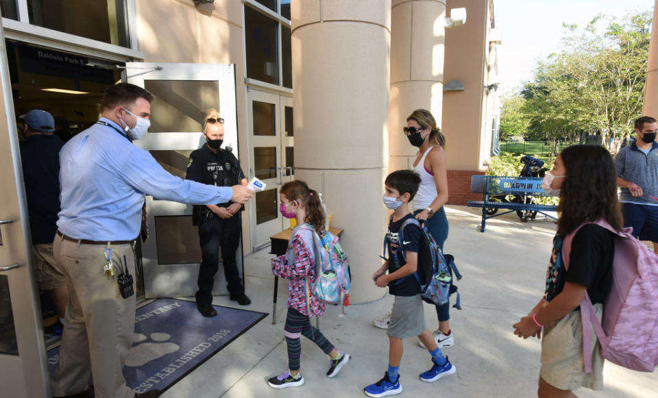 Principal Nathan Hay performs temperature checks on students as they arrive on the first day of classes for the 2021-22 school year at Baldwin Park Elementary School in Orange County, FL. (Paul Hennessy/SOPA Images/LightRocket via Getty Images)