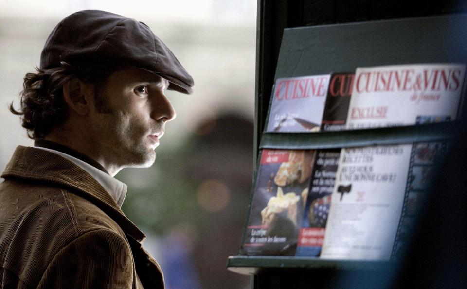 Eric Bana spies on someone near a magazine stand