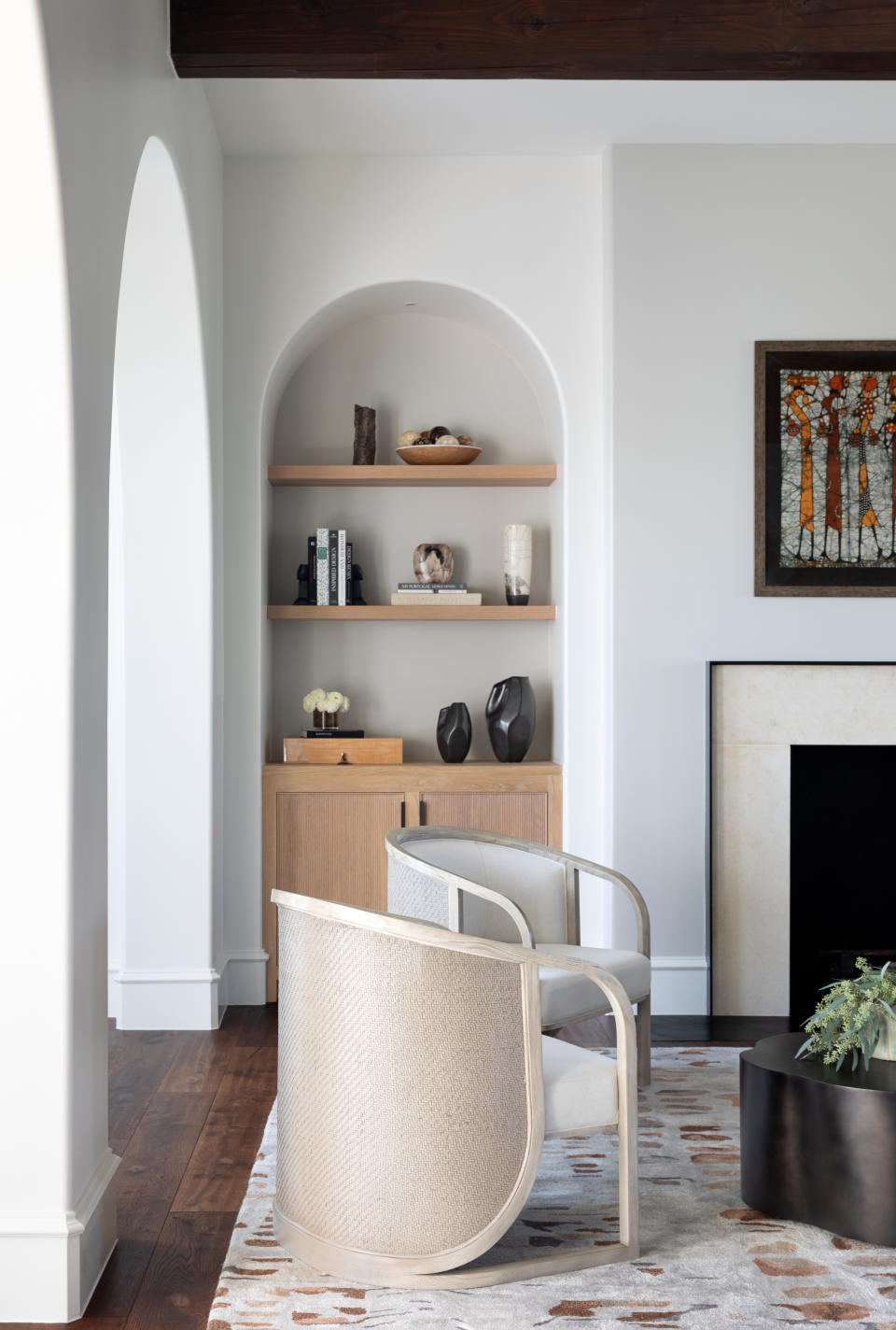 living room in white with bookcase alcove, boucle chair and patterned rug