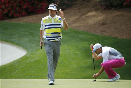 U.S. golfer Bubba Watson waves after making a birdie on the 13th hole as Spain's Sergio Garcia places his ball during the second round of the Masters golf tournament at the Augusta National Golf Club in Augusta, Georgia April 11, 2014. REUTERS/Mike Blake