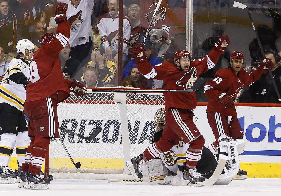 Phoenix Coyotes' Shane Doan, second from left, celebrates his goal against Boston Bruins' Tuukka Rask, bottom right, of Finland, as Coyotes' Brandon McMillan, third from left, and Mike Ribeiro (63) join the celebration as Bruins' Chris Kelly (23) looks on during the first period of an NHL hockey game on Saturday, March 22, 2014, in Glendale, Ariz. (AP Photo/Ross D. Franklin)