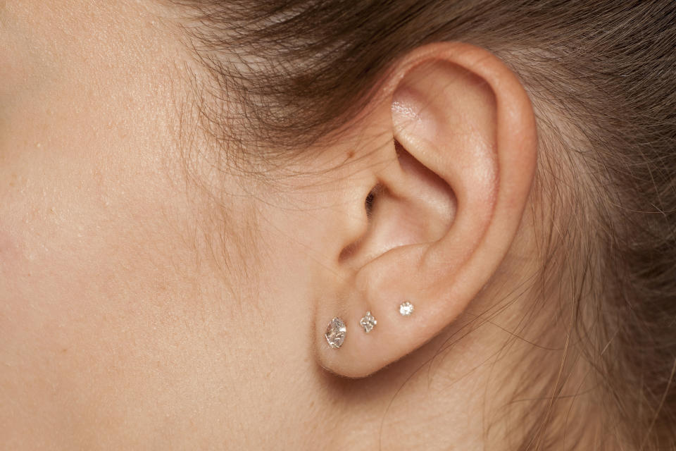 Closeup of female ear with three earrings (Getty Images stock)