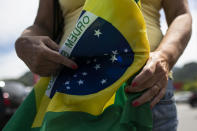 A former supporter of Brazil's President Jair Bolsonaro holds a Brazilian flag during a protest against the government's response in combating COVID-19 and demanding his impeachment, in Rio de Janeiro, Brazil, Sunday, Jan. 24, 2021. (AP Photo/Bruna Prado)